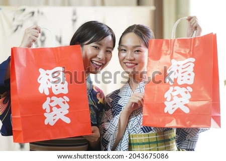 Yukata woman holding a paper bag with "lucky bag" written on it  Royalty-Free Stock Photo #2043675086