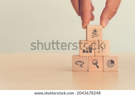 Investment and financial business concept. Man hold wooden cube with money growth icon which standing on  market, strategy, finance, observation and analysis icon. The success factors for investment