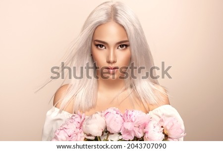 Beautiful asian woman  with hair coloring in ultra blond and flowers. Stylish hairstyle done in a beauty salon. Fashion, cosmetics and makeup Royalty-Free Stock Photo #2043707090