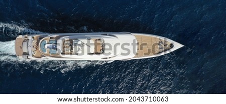 Aerial drone top down photo of luxury yacht with wooden deck and helicopter landing pad cruising deep blue Mediterranean sea