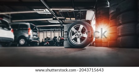 tire at repairing service garage background. Technician man replacing winter and summer tyre for safety road trip. Transportation and automotive maintenance concept  Royalty-Free Stock Photo #2043715643