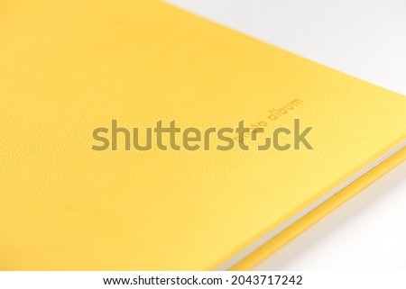 Yellow hardcover photo album on white background. Close-up