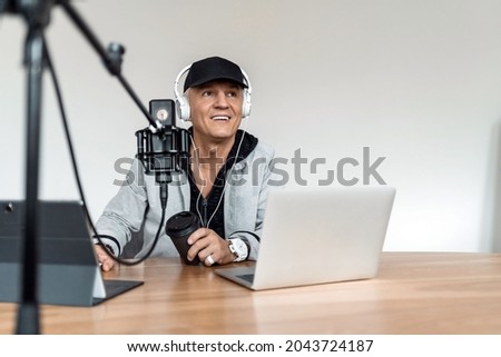 The radio host communicates with people on a direct line. An adult man is working, talking into a microphone about the latest news in the city. A live show with the participation of listeners.