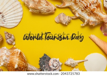 World Tourism Day incription over yellow background, with palm leaves, clam shell, and shoes flat lay background