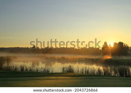 Mist in the air during a early morning. Great nature next to one pond or small lake outside. Golf course. Swedish nature. Nice climate and weather. Vallentuna, Stockholm, Sweden, Scandinavia, Europe. Royalty-Free Stock Photo #2043726866