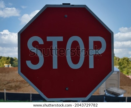 Stop Sign in Front of a Pile of Dirt and a Portable Toilet