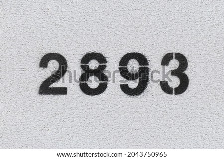 Black Number 2893 on the white wall. Spray paint. Number two thousand eight hundred and ninety three.