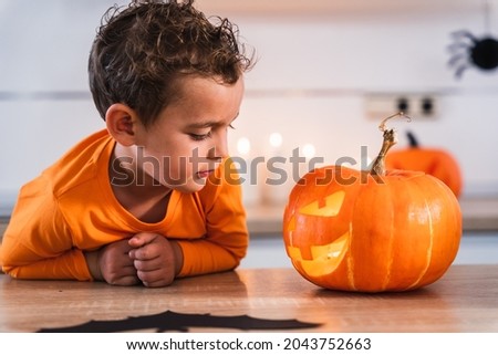 Portrait of a little boy looking at his pumpkin decorated and illuminated for the holiday of halloween at home