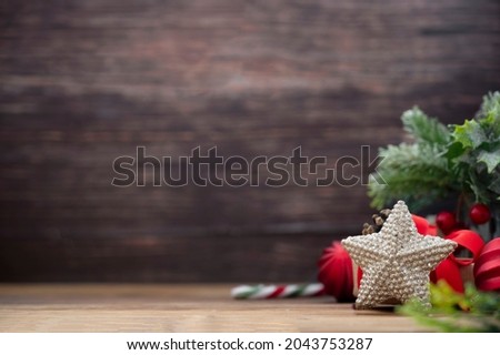 Christmas backdrop. Winter decorations. shiny star with red bauble, fir branches and candy cane. Rustic wooden background. Copy space for text.