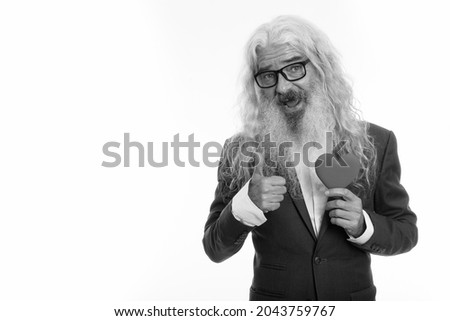 Studio shot of senior bearded businessman in suit isolated against white background in black and white