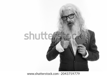 Studio shot of senior bearded businessman in suit isolated against white background in black and white