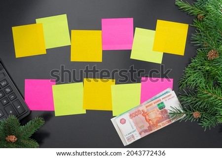 Layout on the theme of New Year 2022 with colorful notes, calculator, money, toys and branches of a Christmas tree on a dark background.