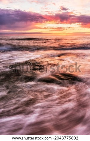 Warm summer sunset seascape with rock and waves on foreground and a colourful cloudy sky on background, Colour Photo, Figueira da Foz, Portugal