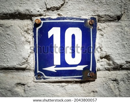 10 on grunge vintage house number plate on exterior wall.