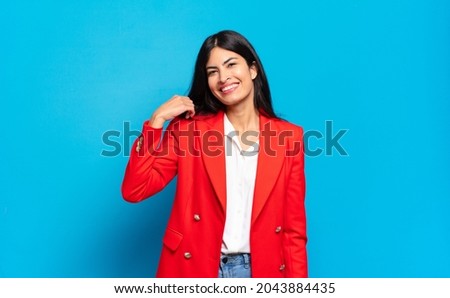 young hispanic businesswoman laughing cheerfully and confidently with a casual, happy, friendly smile