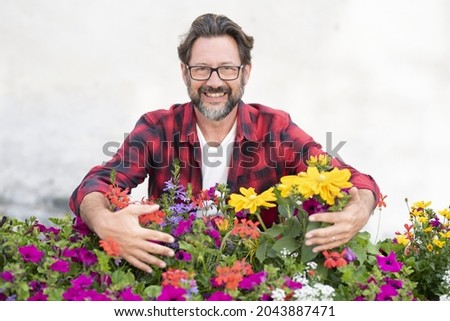 Portrait of mature man holding fresh flowering plants. Smiling man with variety of flowers. Gardening hobby. Male florist taking care of freshly grown flowers - nature floral business store concept