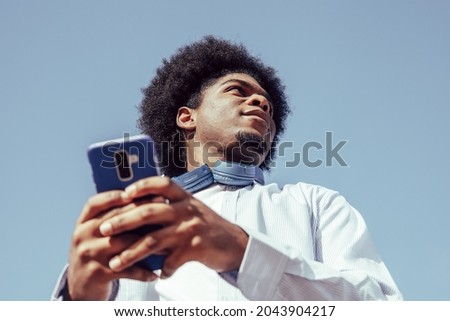 view from below of young african american man using smartphone Royalty-Free Stock Photo #2043904217