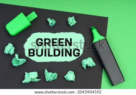 Ecology concept. On a green background, a marker, a black sheet and torn paper with the inscription - Green Building