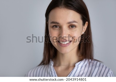 Head shot portrait of smiling young woman with healthy toothy smile and perfect smooth skin on grey background, happy confident successful businesswoman looking at camera, posing for profile picture