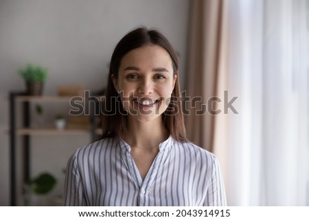 Head shot portrait confident businesswoman, successful entrepreneur, student looking at camera, happy beautiful young woman with healthy toothy smile posing for profile picture, standing at home