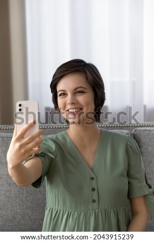 Vertical image of beautiful female expecting baby sit on couch take cute selfie on telephone to keep in memory happy days of pregnancy. Charming future mom posing for self picture at home. Copy space