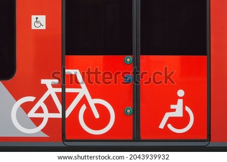 Bicycle sign and disabled person icon on the train carriage door. Transportation of passengers and luggage by public transport. Door opening buttons are at different heights for easy access. Close-up.