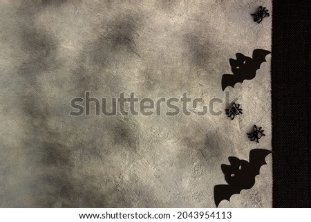 black paper bats and spiders on gray background, modern minimal design.