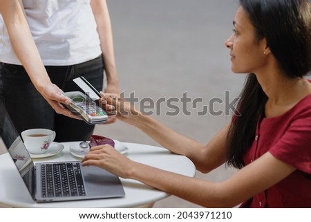 payment by card. contactless payment by bank card or smartphone. african woman pays for an order at a restaurant or food delivery order. modern technology of contactless payment by credit card