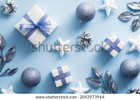 Christmas flat lay composition with gift boxes, balls, branches on blue background. Top view, flat lay.