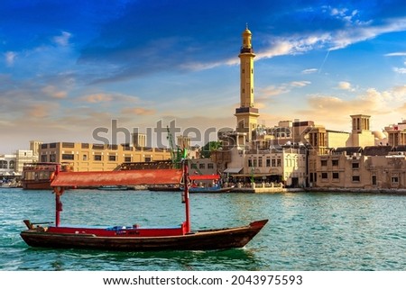 Abra - old traditional wooden boat  and Grand Bur Dubai Masjid Mosque on the bay Creek in Dubai, United Arab Emirates Royalty-Free Stock Photo #2043975593