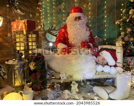 caring santa claus came at night to a  sleeping child in bed and gives gift him. background with glowing lights and garlands.magical scene for merry christmas
