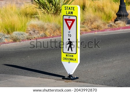 State Law Yield for Pedestrians Within Crosswalk reboundable road sign installed on street.