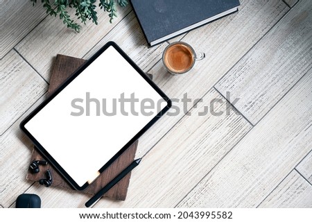 Top view blank screen tablet, gadget, book and coffee cup on wooden table with copy space.