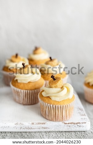 Pumpkin cupcakes with butter cream frosting and hidden filling on table; Thanksgiving mini decorated cakes; fall dessert recipe idea