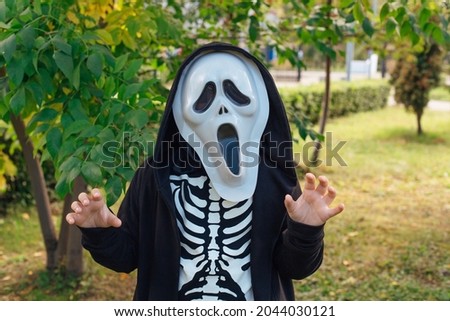 Little boy in a skeleton costume and scream mask is ready to celebrate Halloween.