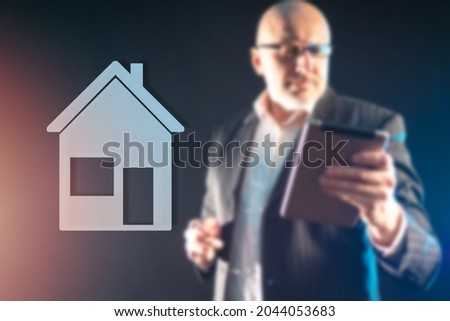Real estate business. A schematic image of a house and a blurred silhouette of a person. Architectural project. Building design. Purchase of real estate. Man chooses new home in mobile application.