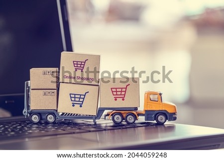Ecommerce, online shopping and delivery service concept : Boxes with shopping carts on a trailer truck on a laptop, depicts e-commerce impacts the trucking industry that retailer needs fast, low price Royalty-Free Stock Photo #2044059248