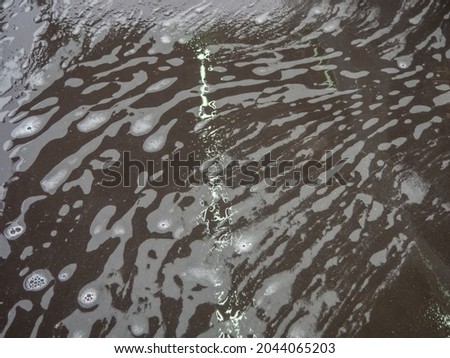 White bath foam with bubbles on the ground. Effect of space and galaxy. Abstract art. Beautiful soap background with waves and foam. Washing suds texture on the dark surface