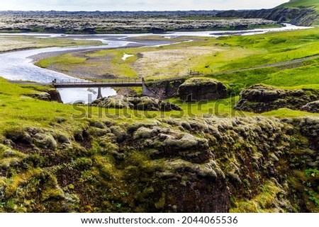 Plain and river. The beginning of mysterious canyon in Iceland - Fyadrarglyufur Canyon. Sheer cliffs stand along a stream with melted glacial water. The concept of active and photo tourism