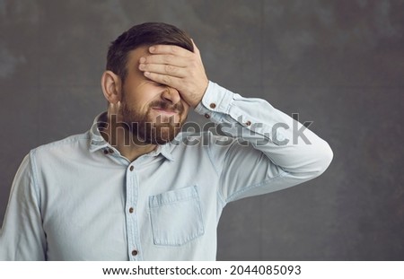 Businessman covers face with hand. Guy facepalms feeling ashamed of terrible mistake or poor memory. Annoyed guilty cringing business manager employee closes face with palm isolated on grey background Royalty-Free Stock Photo #2044085093