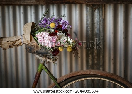 Vintage bike leaning against shed wall with fresh flowers