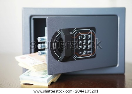Steel safe with money. Hand putting password in the safety money box in hotel room