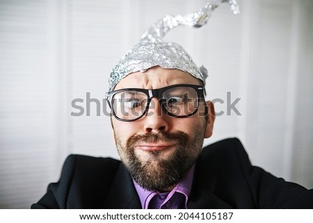 Bearded funny man in cap of aluminum foil. Concept art phobias. Conspiracy theory. Conspiracy. Insanity. Royalty-Free Stock Photo #2044105187