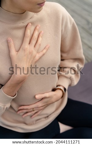 Close-up of a woman's hands on her chest while doing breathing exercises. Caucasian woman sitting in a lotus position, practicing pranayama Royalty-Free Stock Photo #2044111271