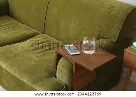 Glass of water with mobile phone on armrest table in room Royalty-Free Stock Photo #2044123769