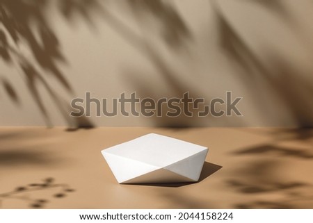 Abstract minimal nature scene - empty stage and polygonal podium on beige background and soft shadows of tree leaves. Pedestal for cosmetic product and packaging mockups display presentation