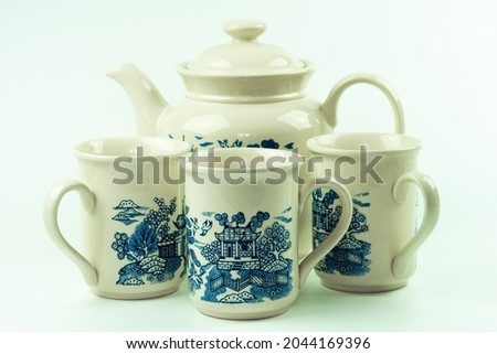 Three china-themed coffee cups and teapot. Porcelain or ceramic.