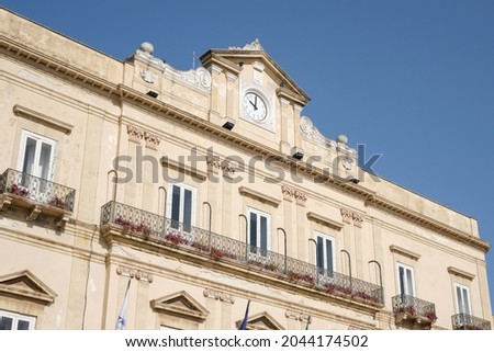 Taranto, Italy - September 19, 2021: partial view of the façade of the building that houses the Town Hall administrative center of the city, visible the clock on top. Royalty-Free Stock Photo #2044174502