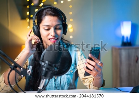 Young Indian girl vlogger live recording or streaming and checking likes, comments or chatting on social media with channel subscribers