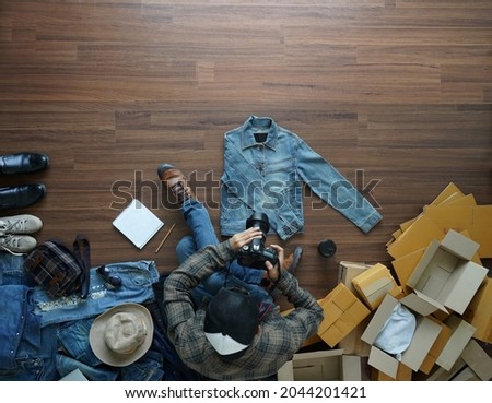 Top view of Selling online ideas concept, Asian men shooting take a photo jeans jacket on wooden floor from home
